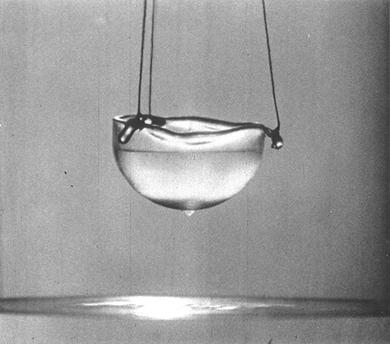Dans un récipient en verre, l’hélium superfluide remonte le long des parois par capilarité et déborde,d’où la goutte en dessous ; Crédits : AlfredLeitner